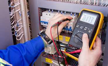 Electrician using a mustimeter to test a switchboard